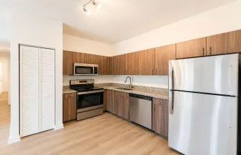Contemporary kitchen featuring wood-finish cabinetry, granite-style countertops, and stainless steel appliances