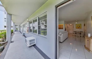 Covered outdoor walkway with grey pillars and a grey ground finish, offering direct access to the interior space