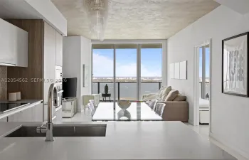 Open Miele kitchen flowing to the living area with floor-to-ceiling bay views