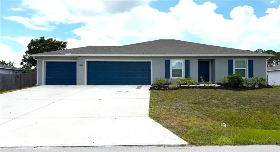 Contemporary stucco exterior featuring a three-car garage, a front entry, and a landscaped garden bed