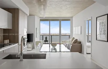 Open Miele kitchen flowing to the living area with floor-to-ceiling bay views