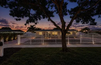 A must-see! Breathtaking twilight curb appeal welcomes you to this private 7,875 sq. ft. homesite featuring a grand motorized gated entrance, expansive stamped concrete circular driveway with additional parking, lush Podocarpus privacy landscaping, impact-rated front door, hurricane shutters, newer August 2023 roof, and beautifully illuminated grounds that create an unforgettable first impression.