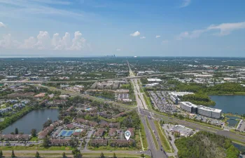 Aerial perspective showcasing a residential community with multiple buildings, two tennis courts, and a central pool area