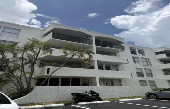 Multi-story stucco exterior with private balconies and mature palm landscaping