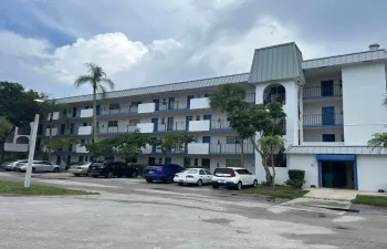 Multi-story building featuring white exterior, blue accents, and a mansard-style roof