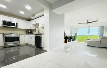 Modern kitchen featuring white cabinetry, stainless steel appliances, granite countertops, and a tile backsplash
