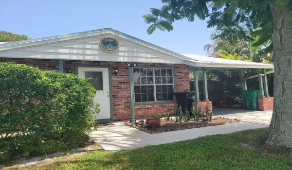 Brick exterior featuring a gabled roofline with decorative accent, a covered carport, and a paved walkway leading to the entrance