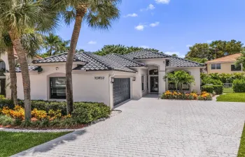 Contemporary stucco residence featuring a dark tile roof, a paver driveway, and an arched entry