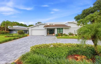 A striking first impression begins with a sweeping paver driveway, lush tropical landscaping, and timeless architectural details that set this home apart. Sitting on a beautifully maintained oversized-corner lot within the gated highly sought after community of Seagate Country Club, this home offers exceptional curb appeal, mature greenery, and a sense of privacy that is increasingly difficult to find in central Delray Beach.