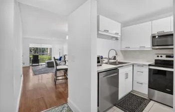 Kitchen with white cabinetry, newer stainless steel appliances, and white countertops