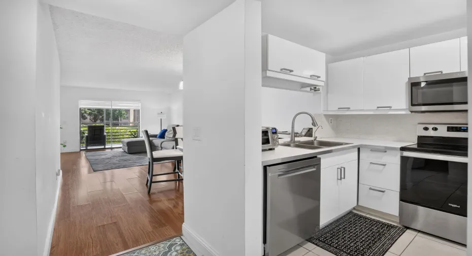 Kitchen with white cabinetry, newer stainless steel appliances, and white countertops