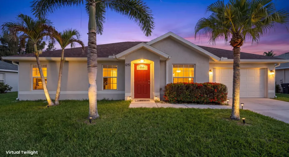 Single-story stucco exterior featuring a prominent red entry door, an integrated two-car garage, and established palm trees