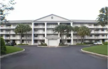 Three-story multi-unit structure featuring a classical architectural facade, multiple balconies, and a central portico with columns