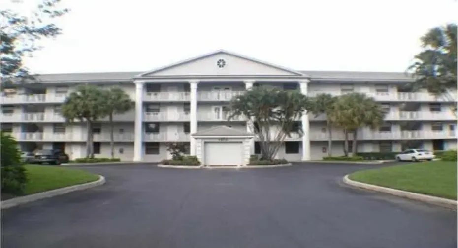 Three-story multi-unit structure featuring a classical architectural facade, multiple balconies, and a central portico with columns