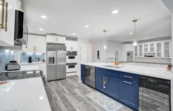 Spacious kitchen featuring a large island with blue cabinetry, white countertops, and stainless steel appliances
