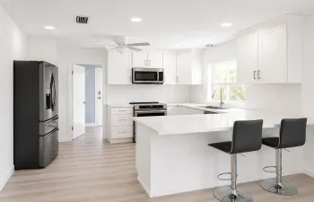 Modern kitchen featuring white shaker cabinetry, stainless steel appliances, and wood-finish flooring