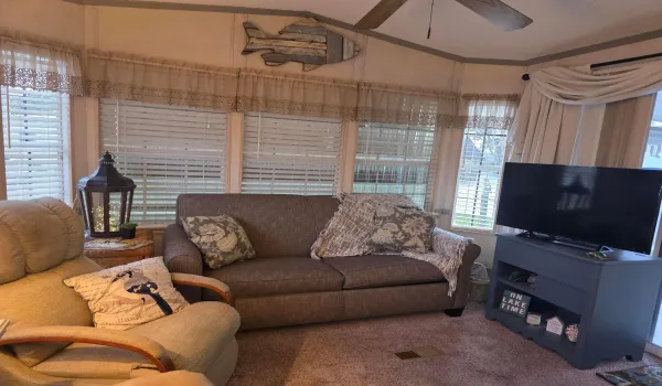 Sunroom featuring multiple windows with blinds, carpeted flooring, a ceiling fan, and a built-in media console