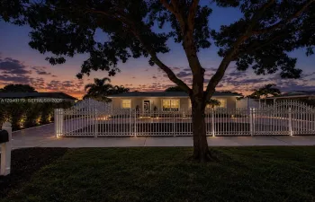 A must-see! Breathtaking twilight curb appeal welcomes you to this private 7,875 sq. ft. homesite featuring a grand motorized gated entrance, expansive stamped concrete circular driveway with additional parking, lush Podocarpus privacy landscaping, impact-rated front door, hurricane shutters, newer August 2023 roof, and beautifully illuminated grounds that create an unforgettable first impression.