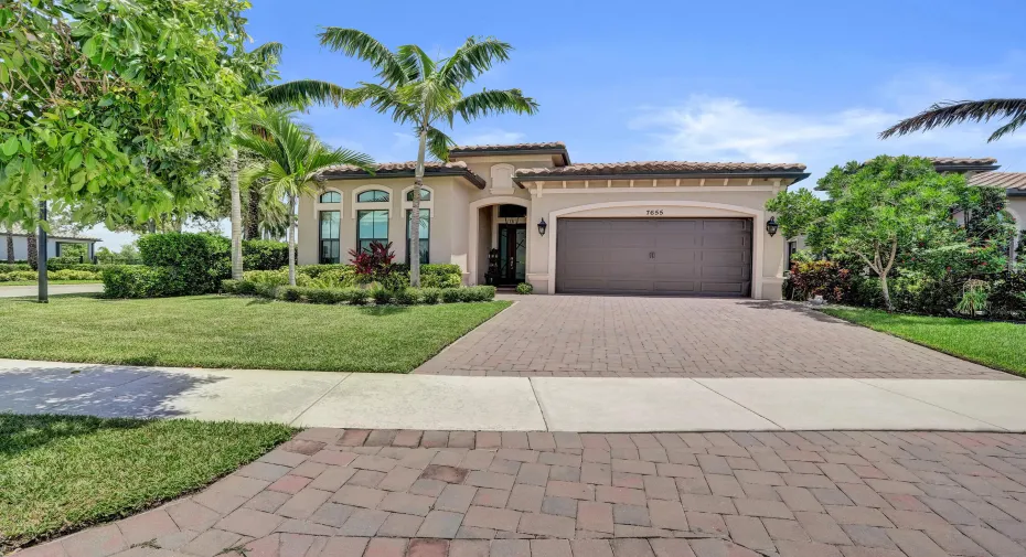 St. Lucia model w barrel tiled roof, stucco exterior, arched windows, two car attached garage and brick paver driveway