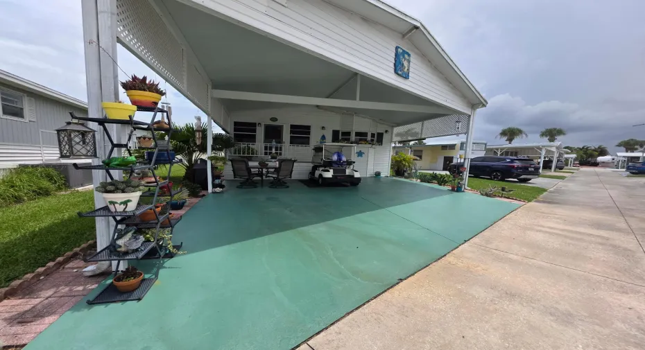 Covered carport with green-painted concrete flooring, offering sheltered outdoor living space