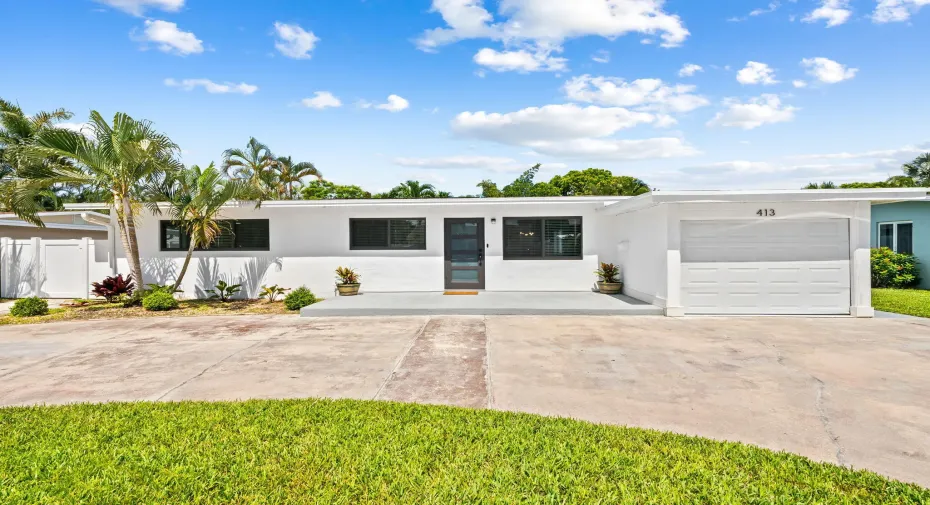 Modern white exterior with dark-framed windows, a sleek entry door, and a white garage door