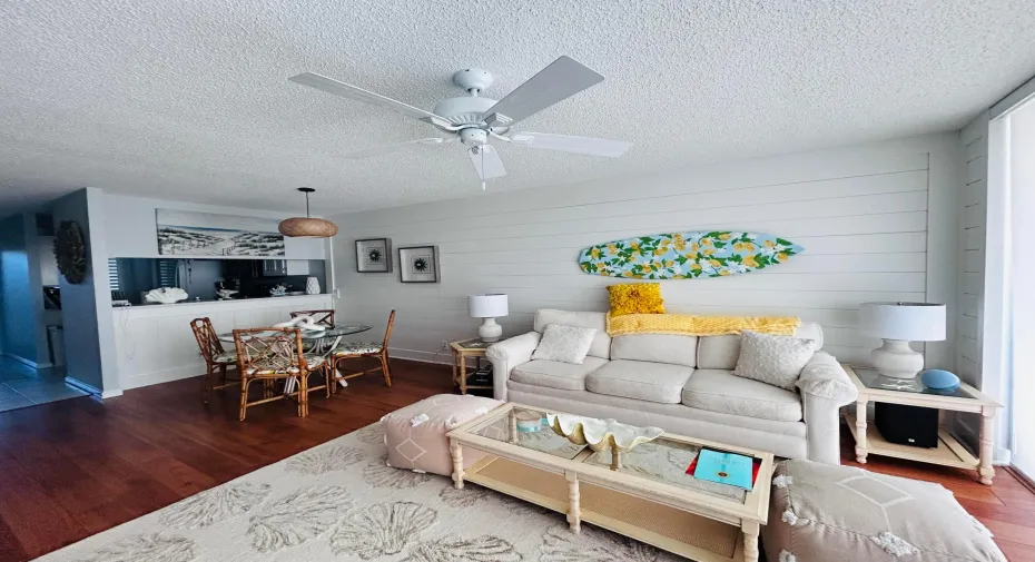 Open-concept living space with wood-finish flooring, a contemporary ceiling fan, and shiplap accent wall