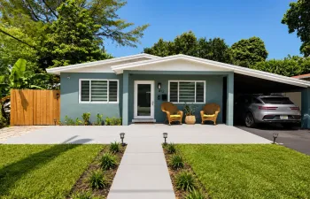 Contemporary exterior with a covered carport, a concrete driveway, a wood fence, a landscaped front yard, and a paved walkway with ground lighting