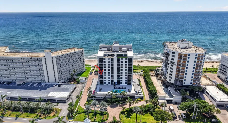 Oceanfront mid-rise building featuring a modern facade, private balconies, and an outdoor swimming pool