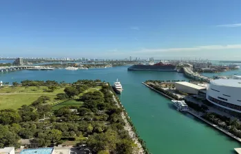 Expansive waterfront panorama showcasing a marina, urban parkland, and distant city skyline