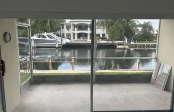 Screened porch with gray tile flooring overlooking the water.