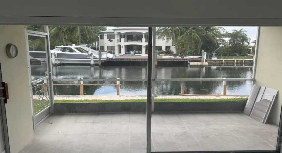 Screened porch with gray tile flooring overlooking the water.