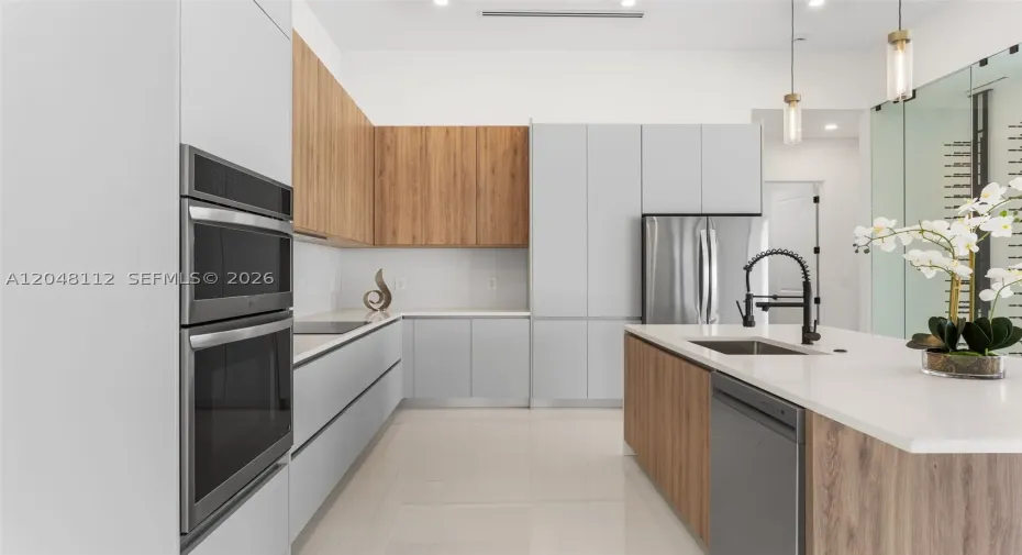 The EXPANSIVE ISLAND offers FLEXIBLE SEATING for CASUAL DINING or FORMAL GATHERINGS, and a FULL QUARTZ BACKSPLASH adds MODERN SOPHISTICATION