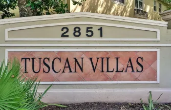 Entry monument featuring tan stucco, a prominent tiled sign with 