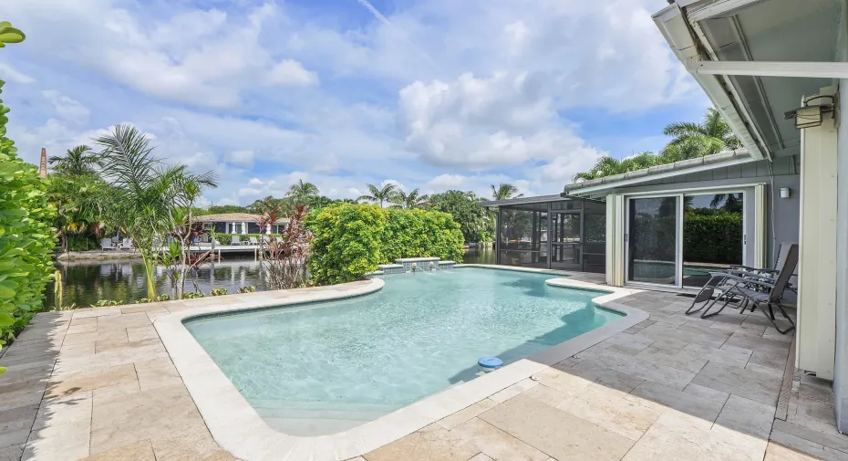 Resort-style pool with a waterfall feature and integrated spa, surrounded by natural stone pavers