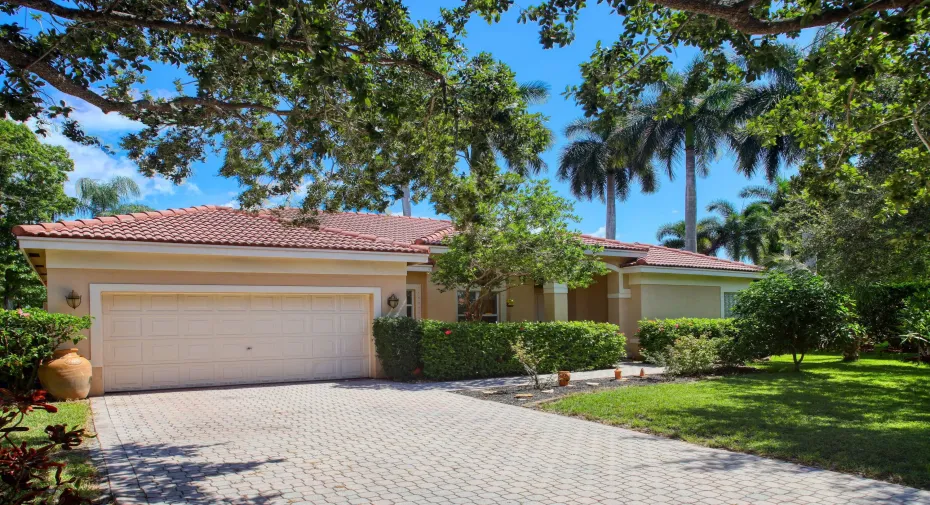 Beautiful front elevation featuring a tile roof, mature tropical landscaping, oversized driveway, and two-car garage in the desirable Yardley Estates community of Coral Springs.