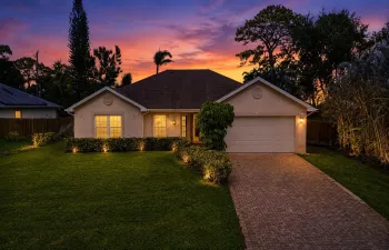 Single-story residence featuring a paved driveway, a two-car garage, and a lush green lawn