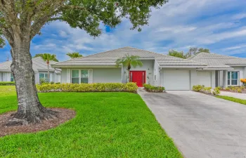 Contemporary single-story residence featuring a striking red entrance door, an attached two-car garage, and a tiled hip roof