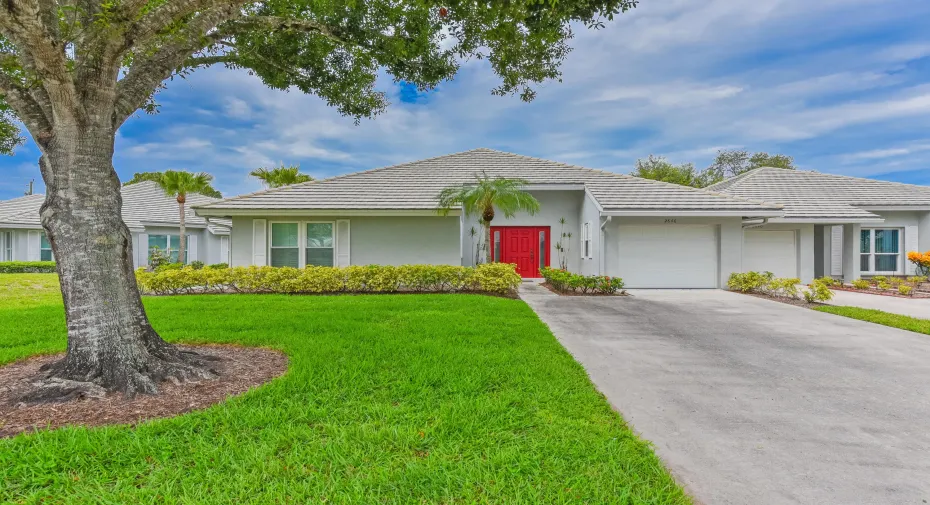Contemporary single-story residence featuring a striking red entrance door, an attached two-car garage, and a tiled hip roof