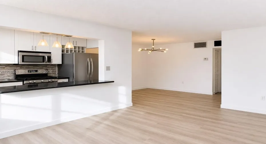 Bright open living area with new flooring, fresh paint and direct views of the updated kitchen.