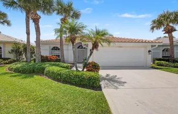 Mediterranean-style exterior with a tile roof, arched windows, an attached two-car garage, mature palm trees, and established landscaping
