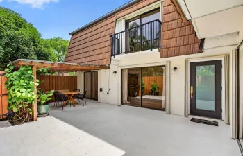 Spacious concrete patio featuring a wooden pergola and privacy fence