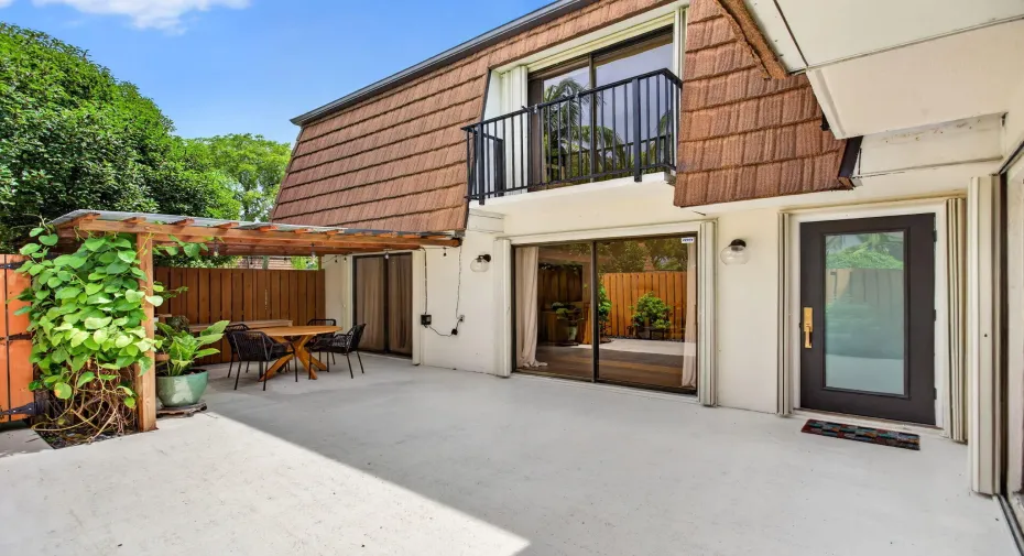 Spacious concrete patio featuring a wooden pergola and privacy fence