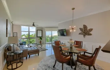 Expansive windows, light-toned flooring, crown molding, a decorative pendant light, and wall paneling