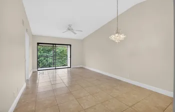 Vaulted ceiling, tiled flooring, ceiling fan, sliding glass doors, and a decorative chandelier