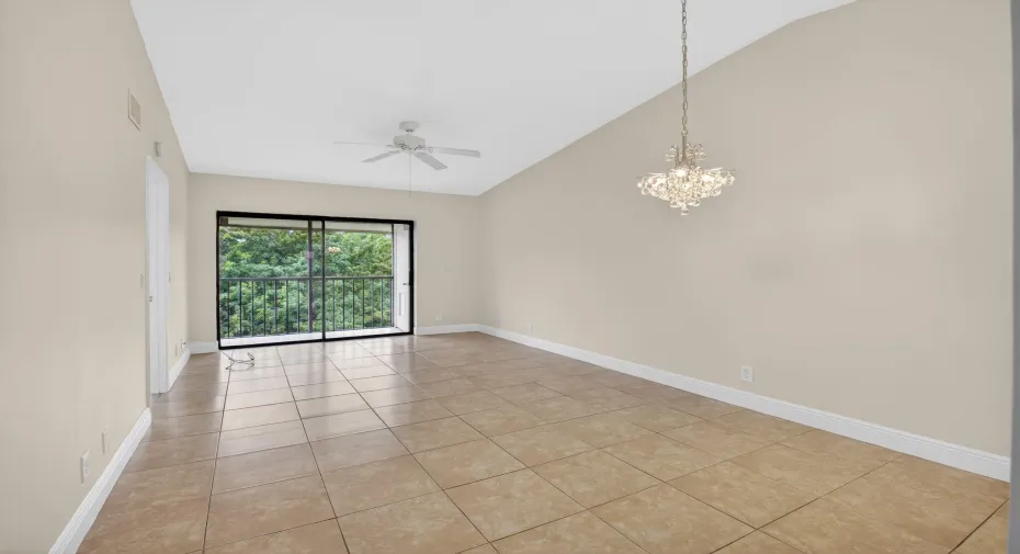 Vaulted ceiling, tiled flooring, ceiling fan, sliding glass doors, and a decorative chandelier