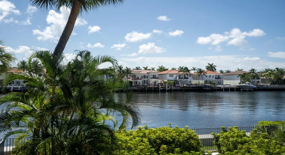 Waterfront scenery featuring a blue sky with scattered clouds, and a diverse range of tropical foliage