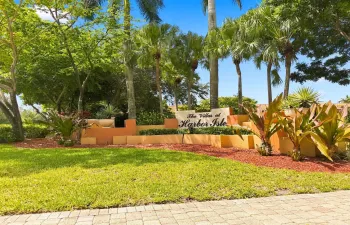 A beautifully landscaped community surrounded by mature tropical foliage, offering an inviting South Florida setting with a community pool, playground, and well-maintained common areas.