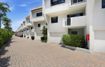 Stucco exterior with white finish, integrated private balconies, attached garages, and a paver driveway