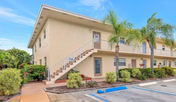 Bright corner condo surrounded by lush tropical landscaping, offering sunny charm, easy access, and inviting curb appeal