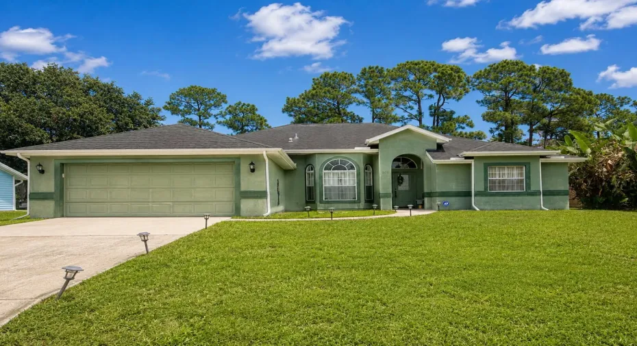 Stucco exterior with an arched entryway, shingle roof, attached garage, and a concrete driveway
